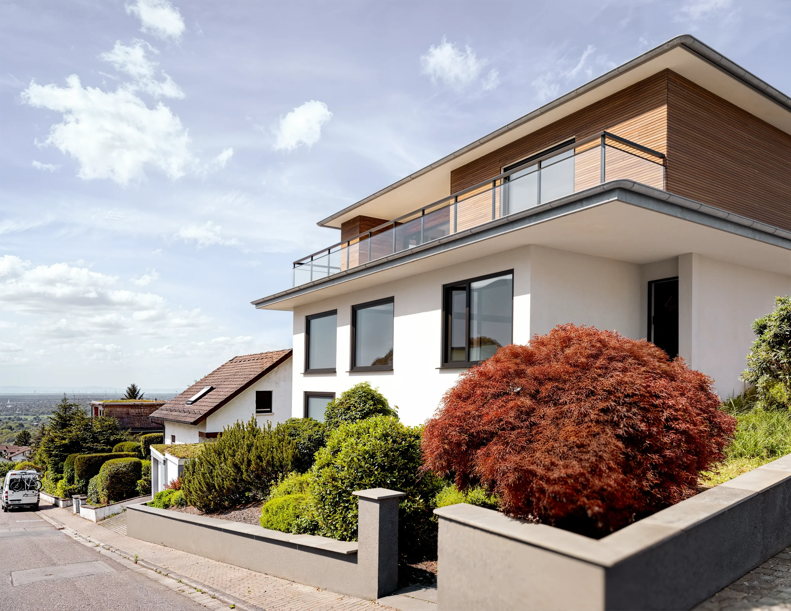Nachher: 3D-Modell des modernisierten Wohnhauses mit Flachdach und Holzfassade, eingesetzt in das Originalfoto