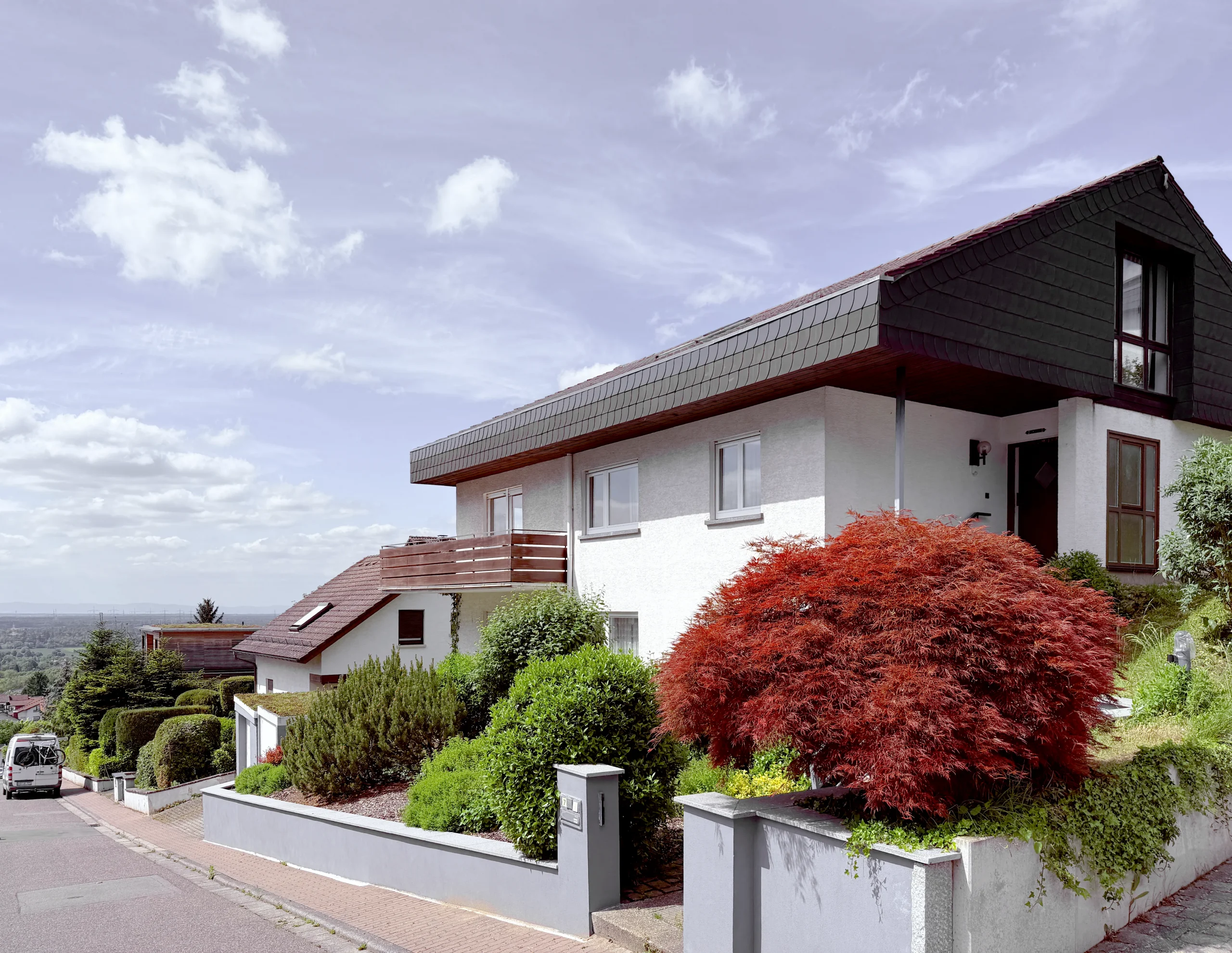 Vorher: Foto des bestehenden Wohnhauses mit Satteldach und Balkon vor der Modernisierung